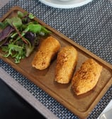Close-up of crispy chicken croquettes served with mixed green salat.