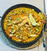 a bowl of Paella food with a spoon and fork