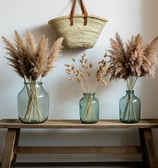 three vases with dried grass in them