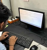 a man sitting at a desk and working with a keyboard and a computer