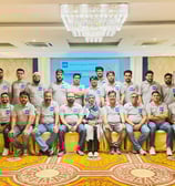 a group of men in grey shirts and jeans are posing for a group photo in a hall