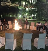 a group of people sitting around a fire pit and having fun