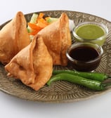 A plate of samosa platter with tamarind and mint chutney