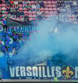 Groupe de supporters de Versailles qui craquent des fumigènes
