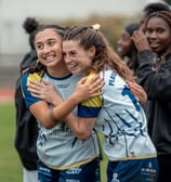 Deux joueuses qui font une accolade en souriant après la victoire