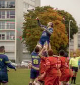 Joueur de rugby porté par ses coéquipiers pour récupérer une balle en touche