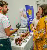 Groupe de personnes qui discutent autour d'un stand qui vend des sauces pimentées