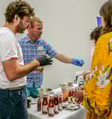 Groupe de personnes autour d'un stand qui dégustent des sauces pimentées