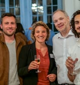 Trois hommes et une femmes qui sourient avec des coupes de champagne dans les mains