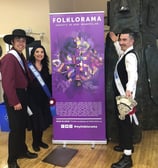 a man and woman standing next to a Folklorama banner