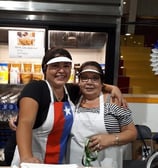 two women standing in front of a counter top