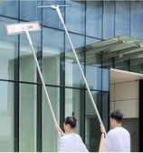 a man and woman cleaning a glass door