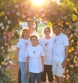 a group of people standing in front of a flower arch