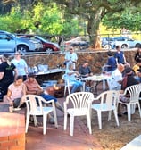 a group of people sitting at tables in a park