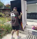 a man in a deanos removals shirt is moving a refrigerator