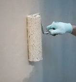 bryiso.fr La photographie illustre la peinture d'un mur extérieur à l'aide d'un rouleau.