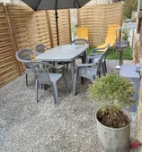 Terrasse ensoleillée avec salon de jardin et parasol. Parfaite pour les repas en plein air. Location de vacances