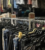 a bunch of clothes hanging on a rack in a warehouse of rental costumes