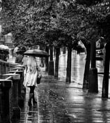 Photo d'une jeune femme femme blonde de dos qui marche sous la pluie a Pregue