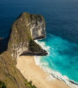 a beach with a cliff and a body of water