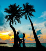 a couple holding hands and standing in front of a sunset
