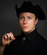 Headshot of a male actor, Vincent Augusto, dressed in a black cowboy costume