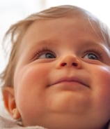 a baby is smiling and looking up her mom