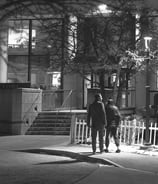 Black and White Photo of a couple walking at night below the glow of a street lamp.