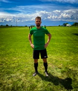 a man in a green shirt and black shorts standing in a field