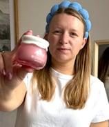 a woman in a white shirt  holding a jar of cream UGC