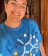 a woman in a blue shirt is smiling and holding a cake