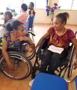 two women in wheelchairs conversing with each other.