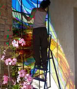 a woman is painting a stained glass window
