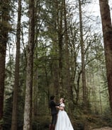 a bride and groom standing in a forest