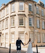 a bride and groom holding hands in front of a building