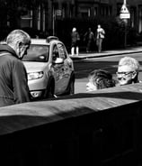 Three women, partially hidden behind a wall chat in the sunshine at Holy Corner, Edinburgh
