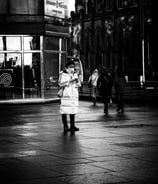 A woman tourist, wearing a face mask, stands at the West End, on her phone. Princes Street, Edinburgh