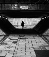 A solitary figure, in silhouette, walks through the underpass at Potterow, Edinburgh