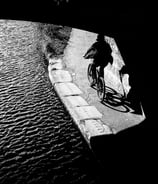 A cyclist on the canal emerges from a bridge in shadow into the light at Meggetland, Edinburgh