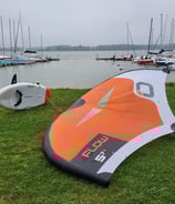 pompowana deska wingfoil i ozone wing na jeziorze Łąka, w tle port oraz jezioro idealne do wingfoila