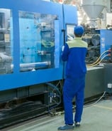 a man in a blue jumpsuit and a blue jumpsuit in a factory
