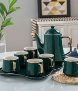 a teapot with cups of tea and a cake