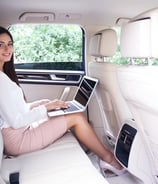 a woman sitting in a car with a laptop