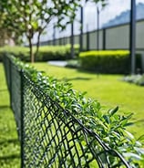 a black chain link fence with a beautiful yard in the background.
