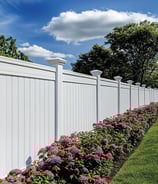 a white vinyl fence with large fence toppers and pink flowers