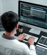 a man sitting at a desk with a laptop and a computer