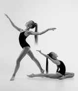 Two gymnasts holding back balance poses during practice.