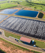 Vista aérea de uma estação de tratamento de esgoto com lagoas de estabilização, cercada por áreas verdes