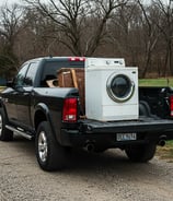 A pickup truck hauling away an old appliance.
