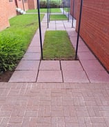 a back court with red monoblock bricks, red concrete slabs and black washing poles